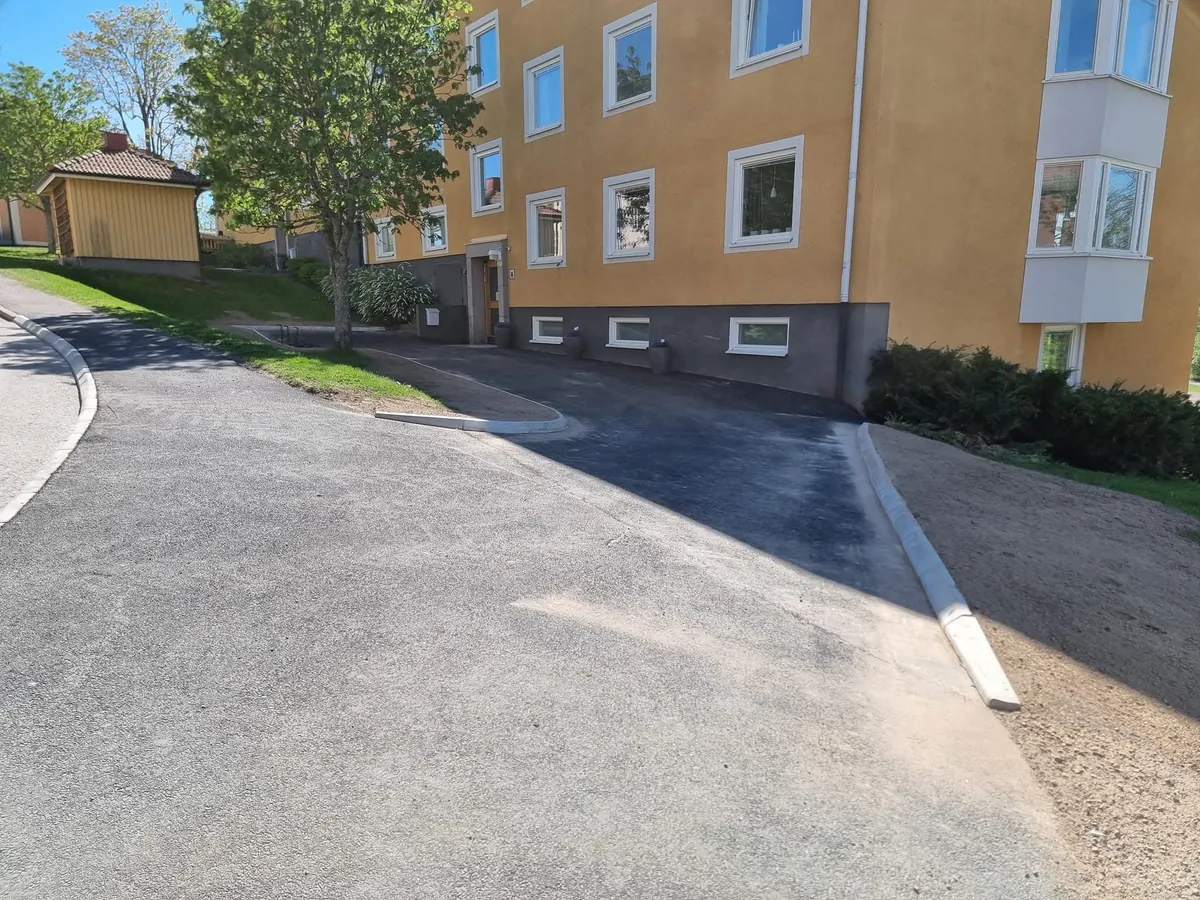 Slät asfalterad infart med ny kantsten efter
